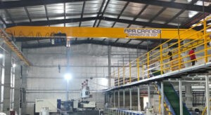 A single girder EOT crane from APR Cranes lifting materials inside a warehouse.